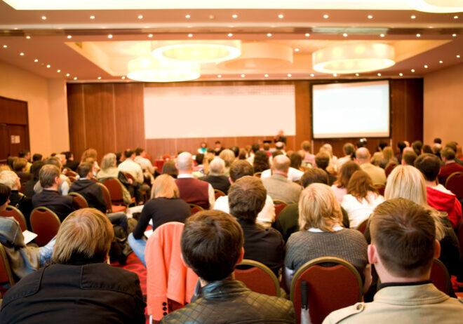 Rear view of many listeners sitting on chairs during lecture at conference